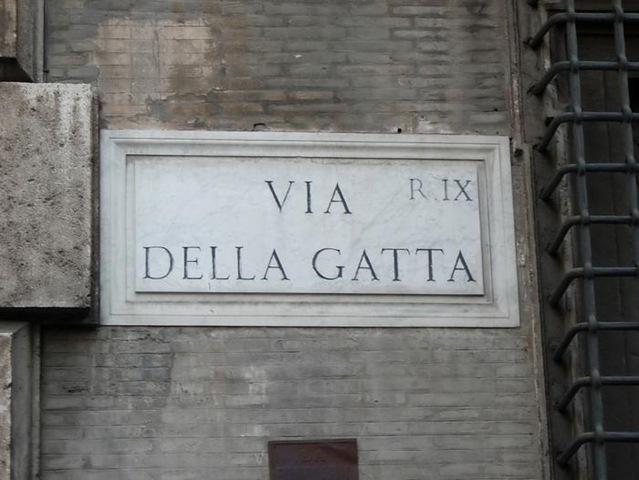 Мраморная кошка на карнизе палаццо в Риме на Via della Gatta